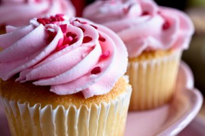 Pink cupcakes with heart-shaped sprinkles.